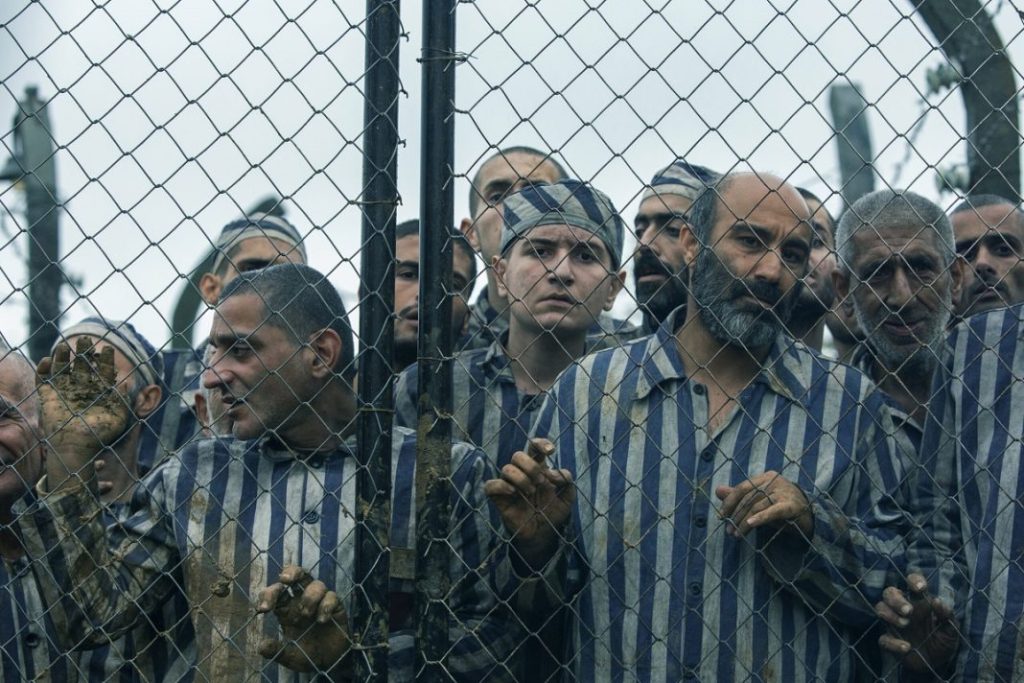 people standing behind the fence