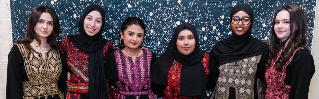 a group of students wearing traditional Palestinian dresses, called thobes.